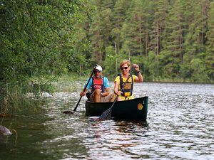 Zwei Menschen fahren Kanu auf einem Fluss in einem Nadelwald