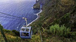 Mit der Seilbahn zum Ort Faja dos Padres auf Madeira Blaue Gondel am Berghang an einer Küste