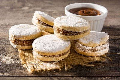 Fünf gefüllte Plätzchen gestapelt vor einer Schüssel mit Creme