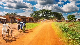 Straße durch eine Stadt in Uganda mit Fahrradfahrern an der Seite