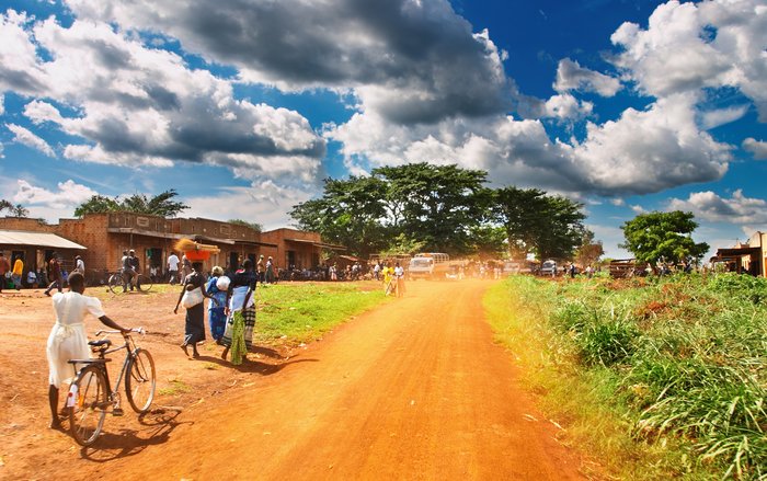 Straße durch eine Stadt in Uganda mit Fahrradfahrern an der Seite