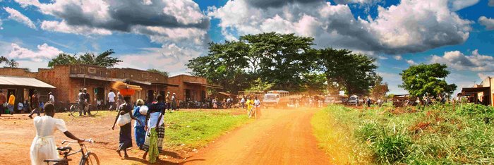 Straße durch eine Stadt in Uganda mit Fahrradfahrern an der Seite