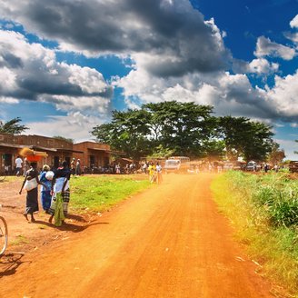 Straße durch eine Stadt in Uganda mit Fahrradfahrern an der Seite