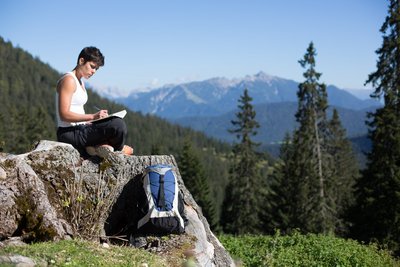 Eine Frau entspannt auf einem Felsen, im Hintergrund das Karwendel-Gebirge in Österreich.