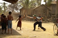 Ein Tourist streckt einem lachendem, einheimischen Kind in Kambodscha die Hand zum High Five entgegen.