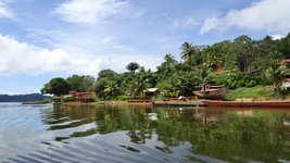 See mit Booten am Ufer und im Hintergrund der Regenwald