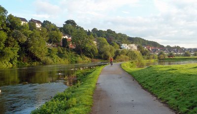 Eine Fahrradfahrerin auf einem Radweg direkt neben der Ruhr