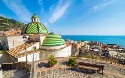 Von einem Platz schaut man über die grün-gelben Dächer von Santa Maria in Maiori bis auf das Meer.