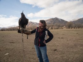 Unsere Gesellschafterin Marion Eine Frau mit Jeans und dunkler Jacke hält auf ihrem gehobenen Arm einen Adler.