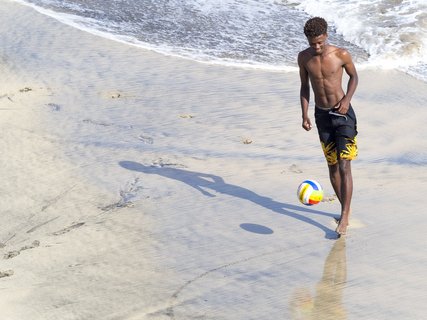 Ein Mann spielt Fußball am Meer