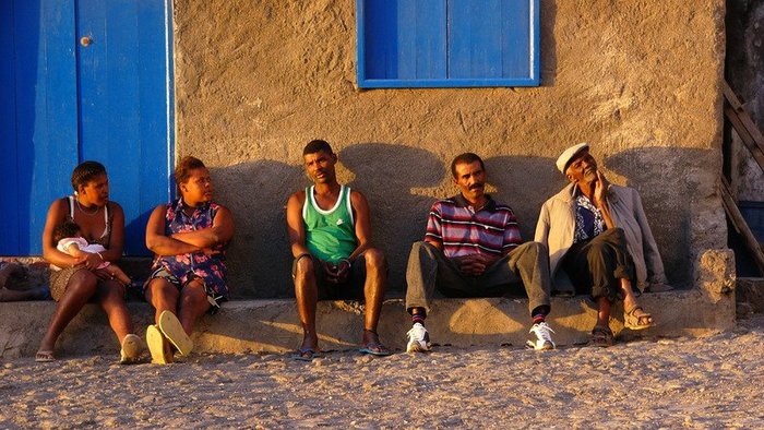 Zwei Frauen und drei Männer sitzen am Straßenrand auf den Kapverden.