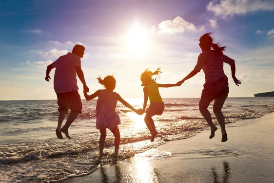 Vierköpfige Familie hüpft fröhlich am Strand