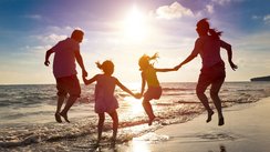 Vierköpfige Familie hüpft fröhlich am Strand