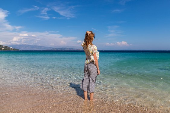 Eine Frau steht mit den Füßen im Meer