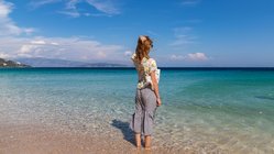Eine Frau steht mit den Füßen im Meer