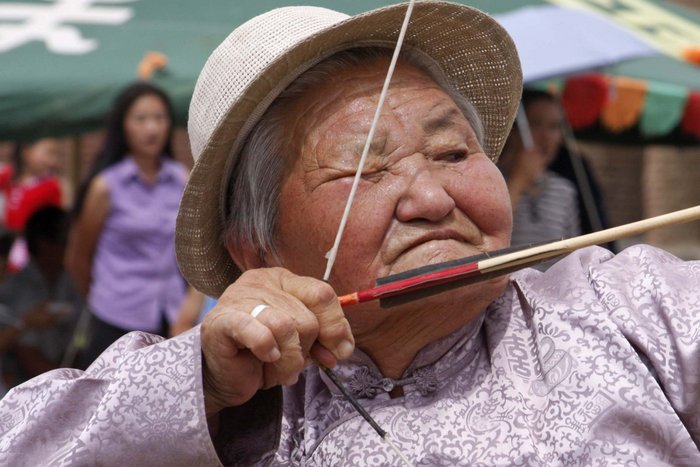 Portrait einer älteren Mongolin, die einen Bogen spannt