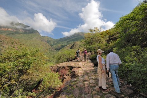 Personen laufen einen Weg (den Camino Real) in der grünen Natur (Chicamocha Canyon) entlang