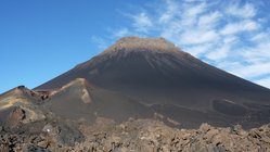 Blick auf den Vulkan Pico de Fogo mit blauem, leicht bewölktem Himmel im Hintergrund.