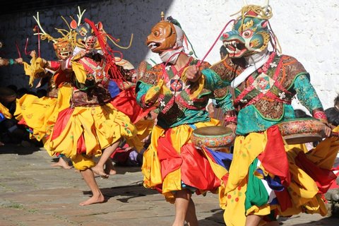 Männer mit Masken und bunter Verkleidung tanzen barfuß nebeneinander