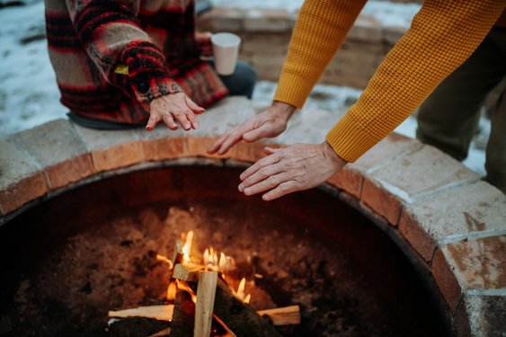 Zwei Menschen wärmen sich an einem Lagerfeuer im Winter