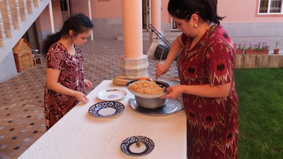 Essen bei einer Familie in Usbekistan Zwei Frauen bereiten das Essen vor an einem Tisch draußen im Garten