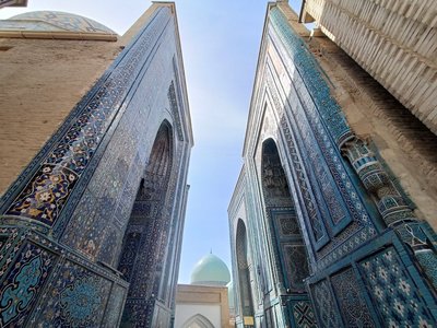 Farbenprächtige Häuserfassaden in Samarkand Das Bild ist links und rechts von hoch aufragenden, farbenprächtigen Häuserfassaden flankiert. Zwischen ihnen erblickt man eine Streifen blauen Himmel.