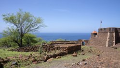 Das UNESCO-Welterbe Cidade Velha gehört zu den Sehenswürdigkeiten der Kapverden. Auf dem Foto ist die alte Festungsanlage zu sehen, dahinter erstreckt sich blauer Ozean.