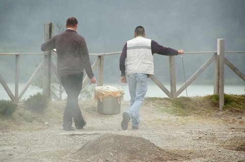 Zwei Menschen tragen einen großen Topf 