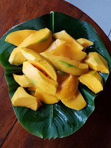 Eine gelbliche Frucht serviert auf einem grünen, großen Blatt