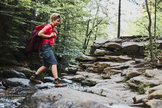 Eine Wanderin überquert einen Fluss