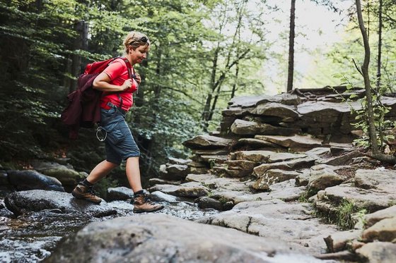 Eine Wanderin überquert einen Fluss