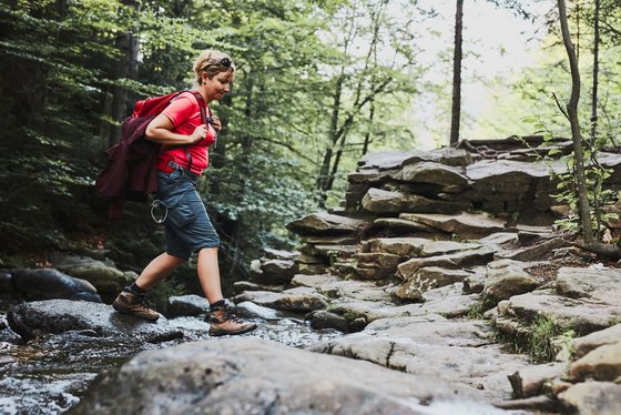 Eine Wanderin überquert einen Fluss Eine Wanderin überquert einen Fluss