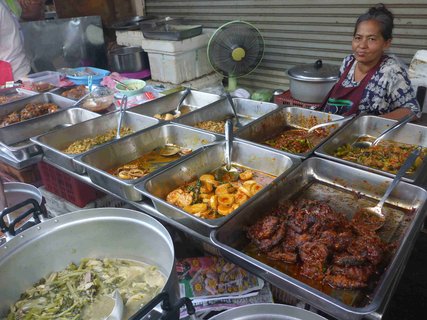 Eine Frau hinter einem Stand bietet verschiedenen Spezialitäten an