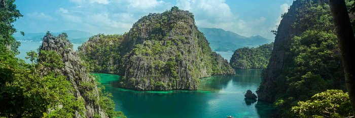 Begrünte Felsen im und am Wasser bilden eine Lagune mit klarem Wasser