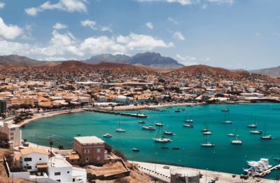 Längs einer Bucht mit türkisblauem Wasser, auf dem Segelboote dümpeln, erstreckt sich der Hauptort São Vicentes Mindelo.