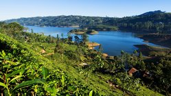 Ein breiter Fluss umgeben von Hügeln und Regenwald in Sri Lanka.