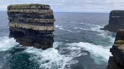 Aus einem bewegten Ozean ragt ein Felsplateau heraus.