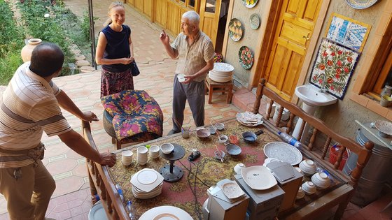 Besuch bei einer kirgisischen Familie Mann einer kirgisischen Familie erklärt unseren Reisegästen über seine Arbeit der Topfmalerei