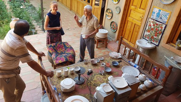 Mann einer kirgisischen Familie erklärt unseren Reisegästen über seine Arbeit der Topfmalerei