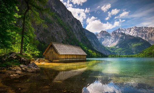 Holzhütte am Rande eines Sees neben Bergen.