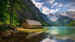 Holzhütte am Rande eines Sees neben Bergen.