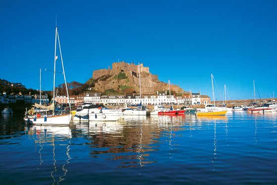 Hinter einem Stadthafen erhebt sich eine Burganlage