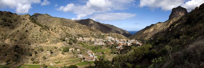 Panoramablick auf ein Dorf im Tal zwischen den Bergen und dem Meer im Hintergrund