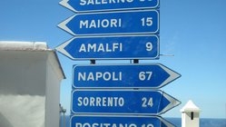Sechs blaue Schilder zeigen die Entfernung zu Orten an der Amalfiküste an.