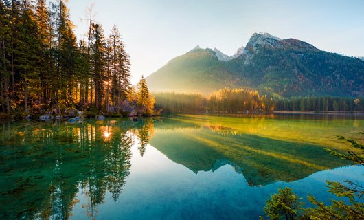 Smaragdgrüner See umgeben von Bergen und Wald
