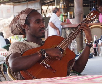 Ein Einheimischer Mann der Kapverden sitzt an einem Tisch und spielt Gitarre