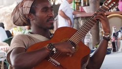 Einheimischer spielt Gitarre Ein Einheimischer Mann der Kapverden sitzt an einem Tisch und spielt Gitarre