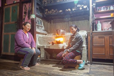 Bewohnerinnen des nordindischen Dorfes Kewzing sitzen vor dem Küchenofen am offenen Feuer.