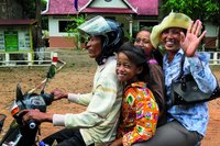 Eine vierköpfige Familie in Laos fährt gemeinsam auf einem Motorroller.