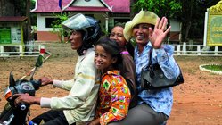 Eine vierköpfige Familie in Laos fährt gemeinsam auf einem Motorroller.
